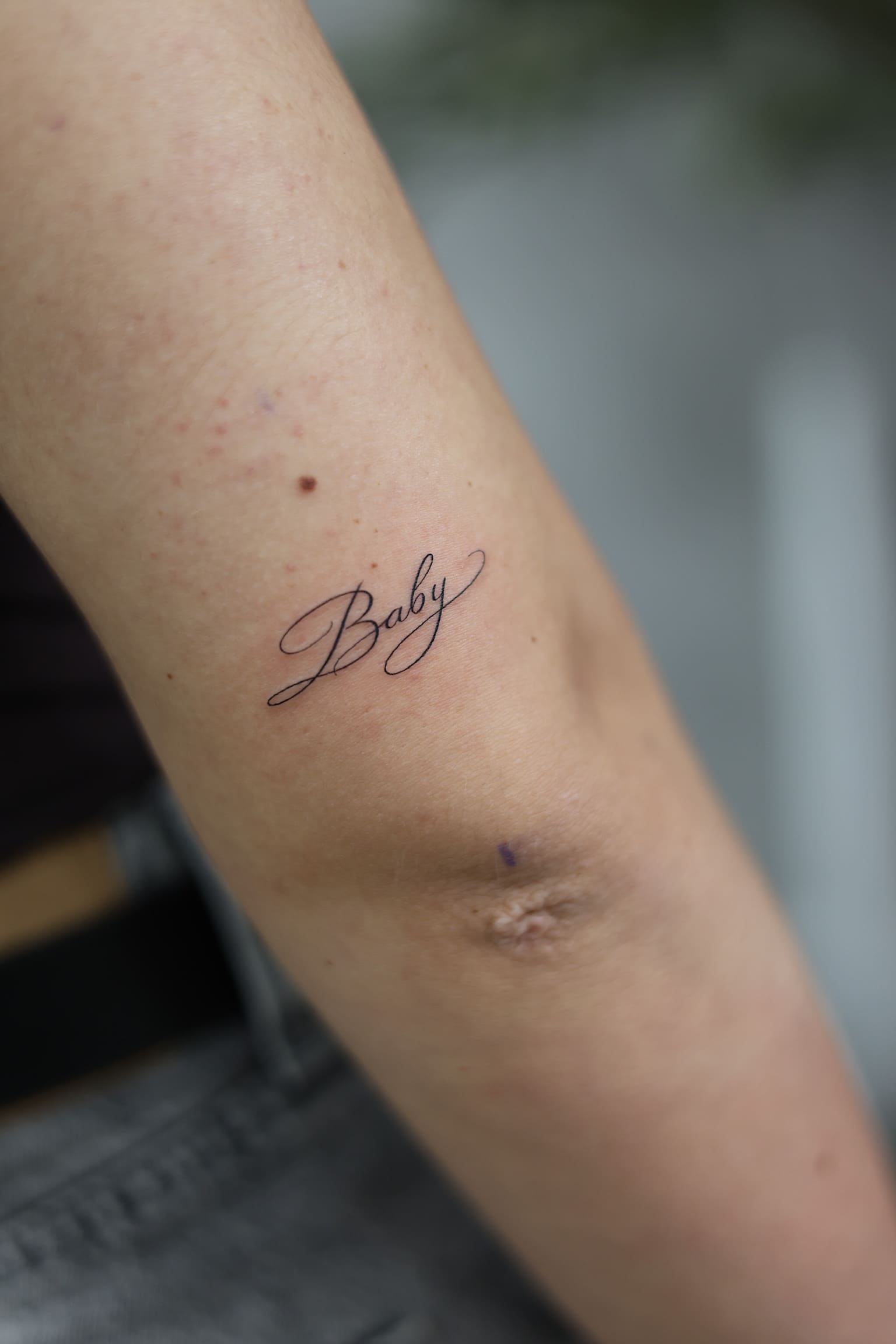 Fine Line Script “Baby” Tattoo
